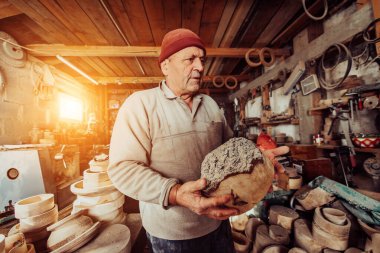 A senior man processing wooden products in a carpentry workshop. 