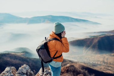 a hiking girl with a backpack on her back watches the morning from the top of the mountain