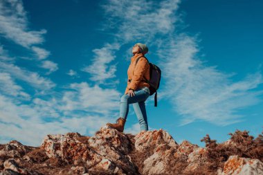 a hiking girl with a backpack on her back watches the morning from the top of the mountain