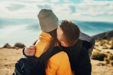a young couple embracing standing on top of a mountain