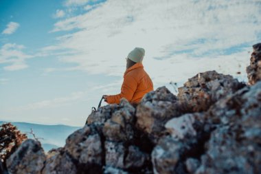 a hiking girl with a backpack on her back watches the morning from the top of the mountain
