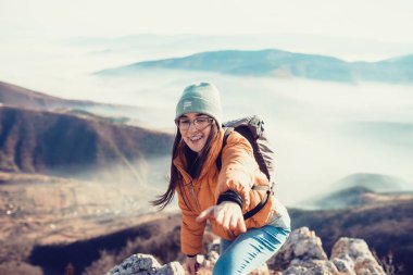 İnsanlar gün doğumunda bir dağa tırmanırken birbirlerine yardım ediyorlar..
