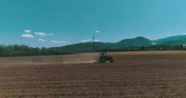 Drone aerial shot of a farmer in tractor seeding, sowing agricultural crops at field.