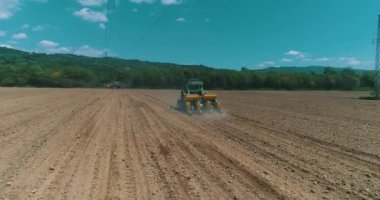 Drone aerial shot of a farmer in tractor seeding, sowing agricultural crops at field.