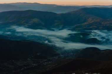 Görünür siluetleri olan dağ siluetleri sabah renkli sislerin arasında.