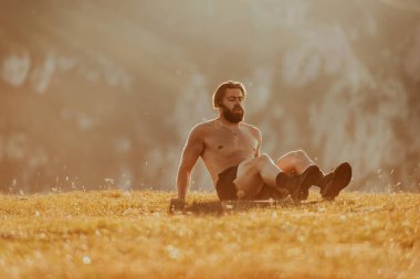 A man doing abs exercises on top of a mountain.