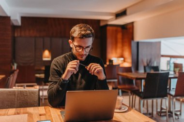Happy young businessman working on a laptop in a cafe. 