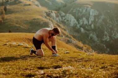 A determined athlete preparing for the start of training on the top of the mountain at sunrise