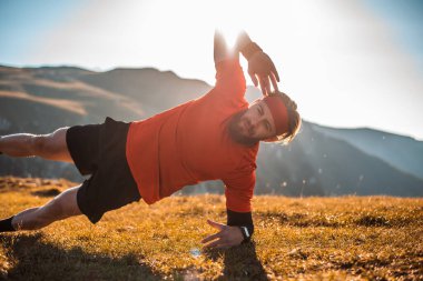 A man doing abs exercises on top of a mountain.