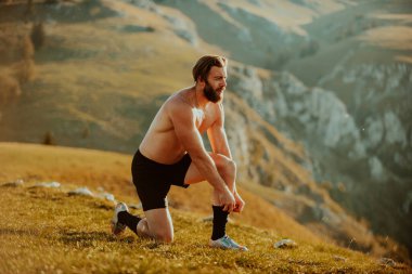 A determined athlete preparing for the start of training on the top of the mountain at sunrise