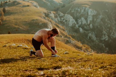A determined athlete preparing for the start of training on the top of the mountain at sunrise