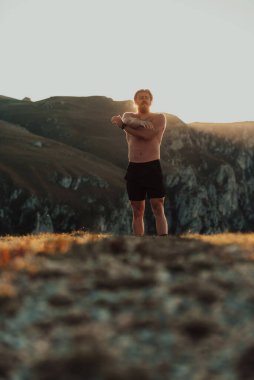 A man stretching his arms after a hard workout in the early hours of the morning.