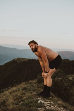 An athlete rests on top of a mountain after exhausting running training
