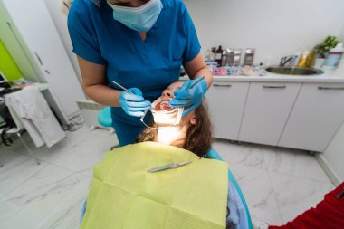 Dentist appointment at a dental clinic, placing braces locks on the teeth and pulling the archwire to fix it. 