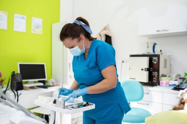 Dentist appointment at a dental clinic, placing braces locks on the teeth and pulling the archwire to fix it. 