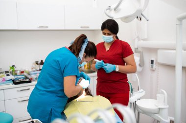 Dentist appointment at a dental clinic, placing braces locks on the teeth and pulling the archwire to fix it. 