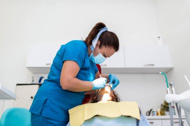 Dentist appointment at a dental clinic, placing braces locks on the teeth and pulling the archwire to fix it. 