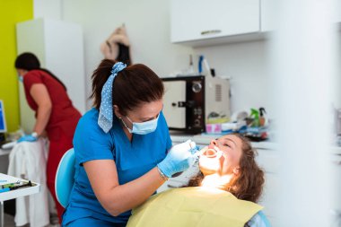 Dentist appointment at a dental clinic, placing braces locks on the teeth and pulling the archwire to fix it. 