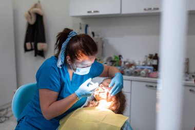 Dentist appointment at a dental clinic, placing braces locks on the teeth and pulling the archwire to fix it. 