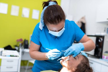 Dentist appointment at a dental clinic, placing braces locks on the teeth and pulling the archwire to fix it. 