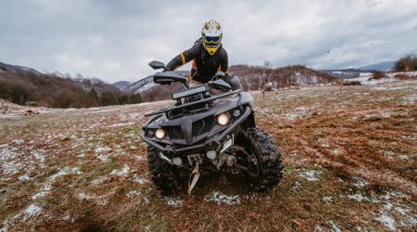 Çamurda bir adam ATV kullanıyor. Çamur ve kar içinde bir ATV avlusunu sürüyordu.. 