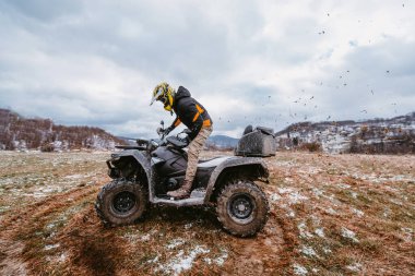 Çamurda bir adam ATV kullanıyor. Çamur ve kar içinde bir ATV avlusunu sürüyordu.. 