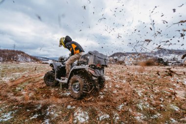 Çamurda bir adam ATV kullanıyor. Çamur ve kar içinde bir ATV avlusunu sürüyordu.. 