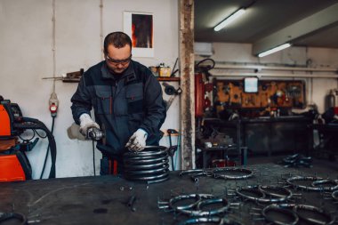 Özel kıyafet ve gözlüklü bir çilingir üretim işinde çalışıyor. Açı öğütücüyle metal işleme. Metal işçiliğinde kıvılcımlar