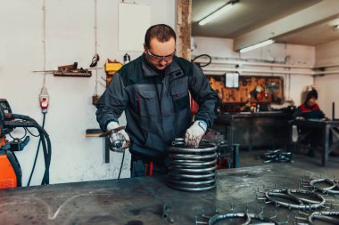 Özel kıyafet ve gözlüklü bir çilingir üretim işinde çalışıyor. Açı öğütücüyle metal işleme. Metal işçiliğinde kıvılcımlar