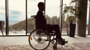 Engelli gülümseyen işadamı tekerlekli sandalyesini kullanarak modern bir ofiste eğleniyor. Özel işyeri ve verimlilik. 