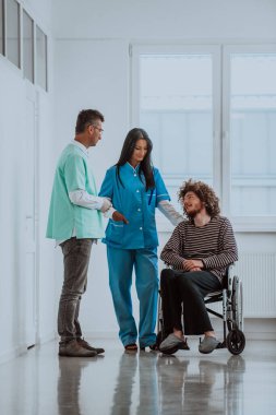 Doktor ve hemşire hastaların sağlığını tartışırken tekerlekli sandalyedeki hasta onların yanında.