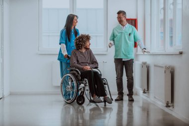 Doktor ve hemşire hastaların sağlığını tartışırken tekerlekli sandalyedeki hasta onların yanında.