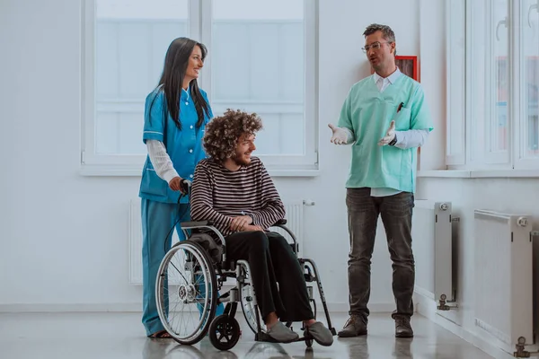 stock image Doctor and a nurse discussing a patients health while the patient, who is in a wheelchair, is present beside them