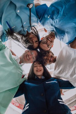  Bir grup doktor, bir hemşire ve bir cerrah, sağlık sektöründe birlik, takım çalışması ve derin bağlantılarını göstererek samimi bir kucaklaşma içinde yakalanıyorlar.