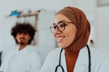 Modern bir toplantı odasında, tesettürlü Müslüman bir kadın doktor meslektaşlarıyla bir tartışmaya girer, çeşitliliğin, dahil olmanın ve işbirlikçi problem çözmenin gücünü örnek gösterir.