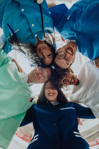  Bir grup doktor, bir hemşire ve bir cerrah, sağlık sektöründe birlik, takım çalışması ve derin bağlantılarını göstererek samimi bir kucaklaşma içinde yakalanıyorlar.