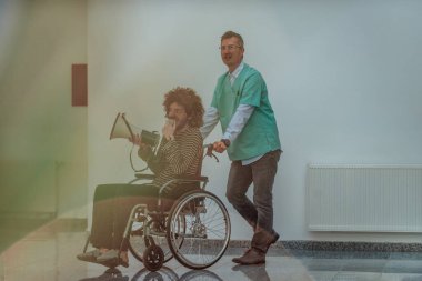 Hasta iletişim için hoparlör kullanırken tekerlekli sandalyedeki hastayı taşıyan bir doktor.