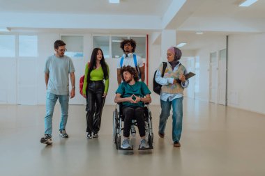 Modern bir üniversitede, aralarında Afro-Amerikalı bir öğrenci ve tesettürlü bir kadının da bulunduğu bir grup öğrenci, tekerlekli sandalyeye mahkum meslektaşlarıyla birlikte koridorda birlikte yürüyorlar.