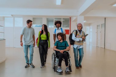 Modern bir üniversitede, aralarında Afro-Amerikalı bir öğrenci ve tesettürlü bir kadının da bulunduğu bir grup öğrenci, tekerlekli sandalyeye mahkum meslektaşlarıyla birlikte koridorda birlikte yürüyorlar.