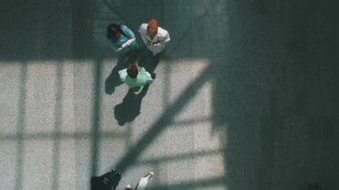 Modern bir hastanenin havadan çekilmiş fotoğrafı ve tekerlekli sandalyedeki bir hastayla konuşan doktorlar..