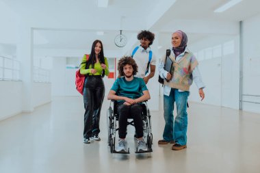 Modern bir üniversitede, aralarında Afrikalı Amerikalı bir öğrenci ve tesettürlü bir kadının da bulunduğu bir grup öğrenci, tekerlekli sandalyeye mahkum meslektaşlarıyla birlikte koridorda yürüyorlar..