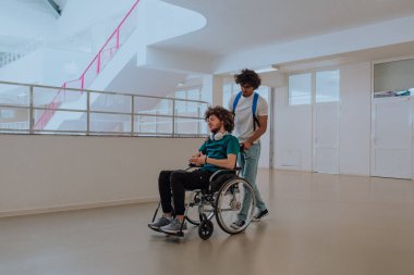 Afrikalı Amerikalı bir öğrenci, arkadaşlarını tekerlekli sandalyeyle modern bir okula sokuyor. Engelli insanlara yardım etme gücünü, ulaşılabilirliğini ve arkadaşlığın gücünü gösteriyor..