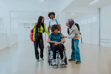 Modern bir üniversitede, aralarında Afrikalı Amerikalı bir öğrenci ve tesettürlü bir kadının da bulunduğu bir grup öğrenci, tekerlekli sandalyeye mahkum meslektaşlarıyla birlikte koridorda yürüyorlar..