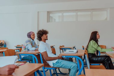 Çeşitli bir grup öğrenci dikkatle dinliyor, aktif olarak katılıyor ve dinamik bir sınıf ortamında modern eğitimi kucaklıyor, işbirliğini teşvik ediyor ve yaratıcılığı teşvik ediyor.