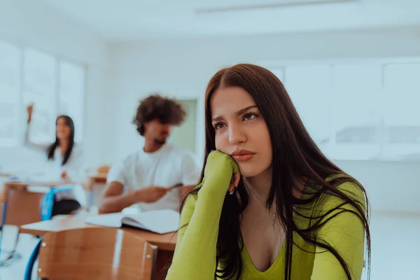 A weary-looking student sitting in front of a group of diverse students in a modern classroom, capturing the blend of exhaustion, learning, and collaboration in their academic journey.