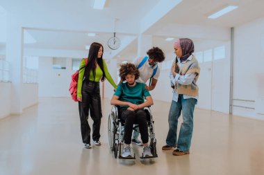 Modern bir üniversitede, aralarında Afrikalı Amerikalı bir öğrenci ve tesettürlü bir kadının da bulunduğu bir grup öğrenci, tekerlekli sandalyeye mahkum meslektaşlarıyla birlikte koridorda yürüyorlar..