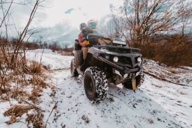 Genç ve maceraperest bir çift, karlı dağlık arazide ATV Quad sürerken aşkın ve heyecanın neşesini kucaklıyor.. 