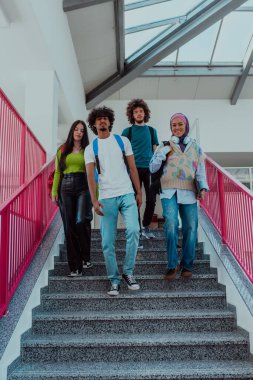 Aralarında Afrika kökenli Amerikalı bir adam ve tesettürlü Müslüman bir kızın da bulunduğu bir grup öğrenci, üniversitenin modern koridorlarında birlikte yürüyorlar.