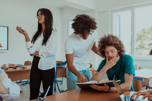 stock image A diverse group of students gathers in a modern school classroom, passionately engaging in lively discussions about various projects, embracing teamwork and utilizing technology to enhance their