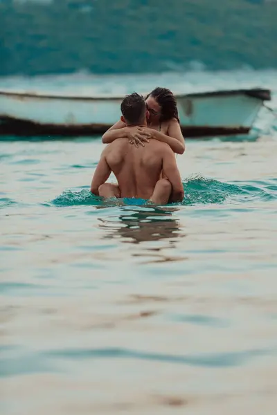 日没の静かな海の美しさの中で情熱的なキスを共有するロマンチックな若いカップル — ストック写真